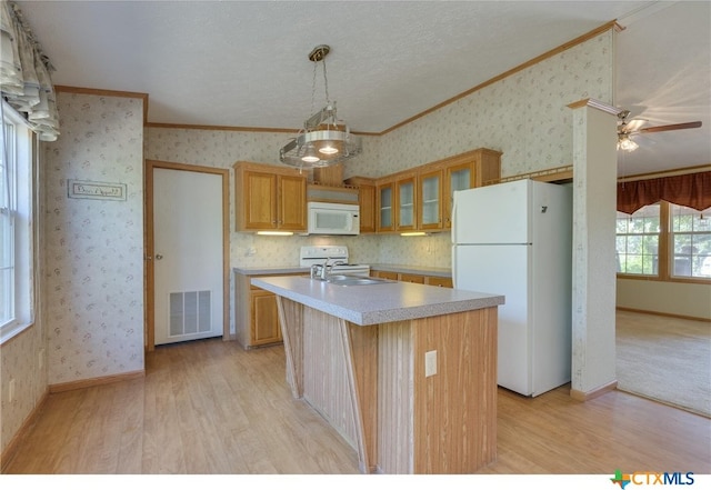 kitchen featuring a kitchen island with sink, crown molding, light hardwood / wood-style floors, white appliances, and ceiling fan with notable chandelier