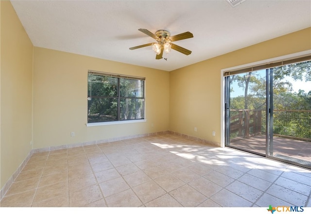 empty room featuring a healthy amount of sunlight, ceiling fan, and light tile patterned floors