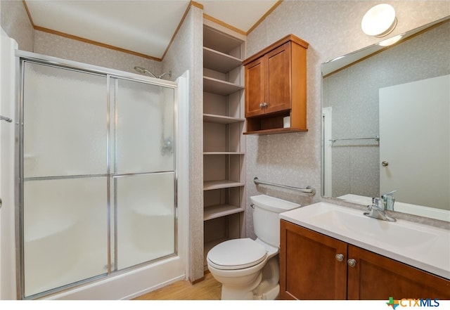 bathroom with toilet, hardwood / wood-style floors, ornamental molding, vanity, and a shower with shower door