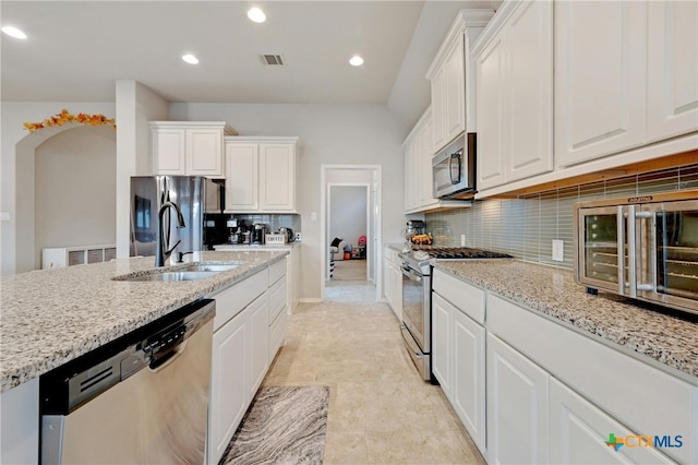 kitchen with white cabinets, appliances with stainless steel finishes, light stone counters, and tasteful backsplash