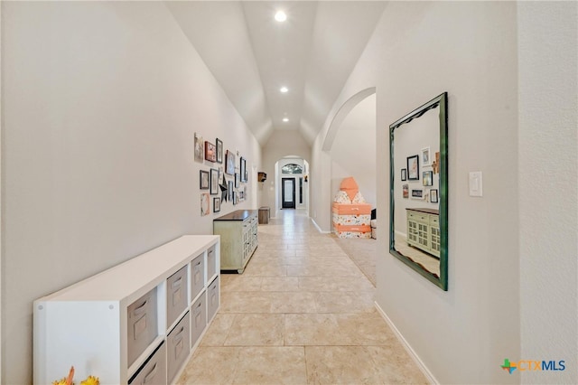 corridor featuring arched walkways, lofted ceiling, recessed lighting, and baseboards