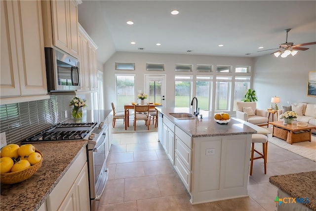 313 Durata Dr, San Marcos, TX 78666 - kitchen featuring appliances with stainless steel finishes, a sink, a kitchen bar, decorative backsplash, and open floor plan