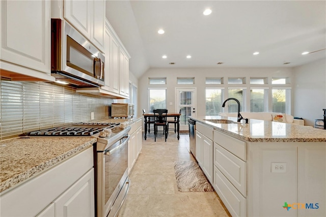 kitchen featuring stainless steel appliances, a sink, backsplash, recessed lighting, and a center island with sink