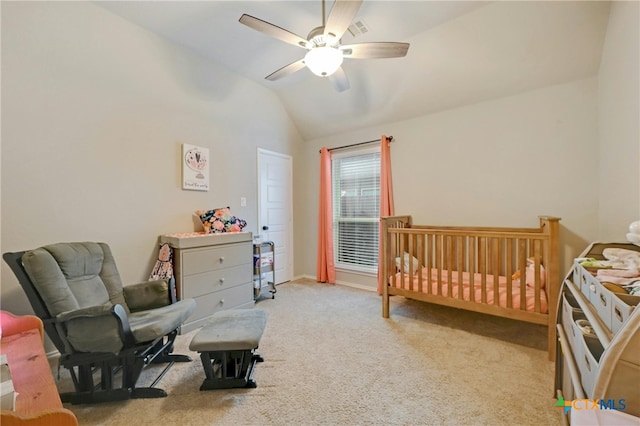 bedroom featuring light colored carpet, a nursery area, lofted ceiling, and ceiling fan