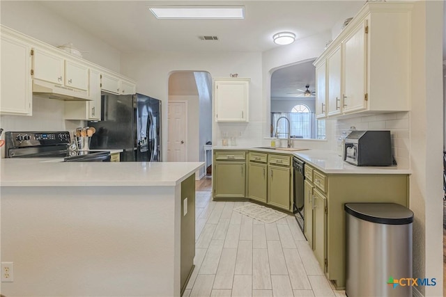 kitchen featuring a sink, arched walkways, under cabinet range hood, visible vents, and black appliances