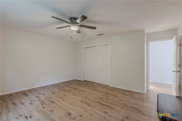 unfurnished bedroom featuring a ceiling fan, baseboards, visible vents, and light wood-style flooring