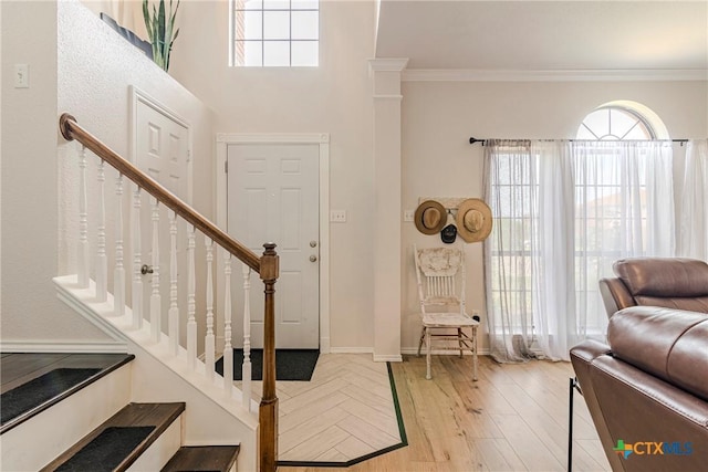 foyer entrance with stairs, crown molding, baseboards, and light wood-type flooring