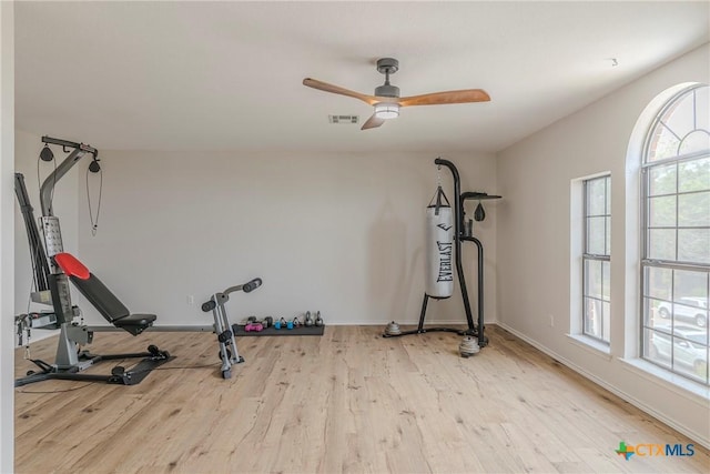 exercise room featuring baseboards, ceiling fan, wood finished floors, and visible vents