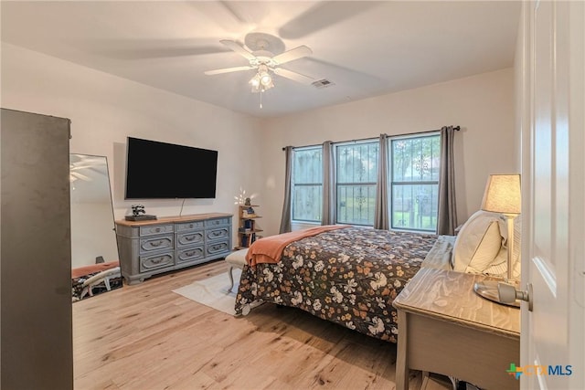 bedroom with a ceiling fan, wood finished floors, and visible vents