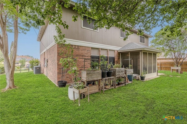 back of property with central air condition unit, fence, a sunroom, and brick siding