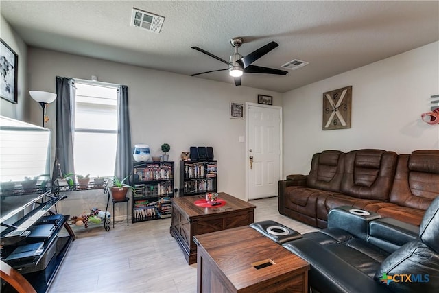 living room featuring ceiling fan, a textured ceiling, and light wood-type flooring