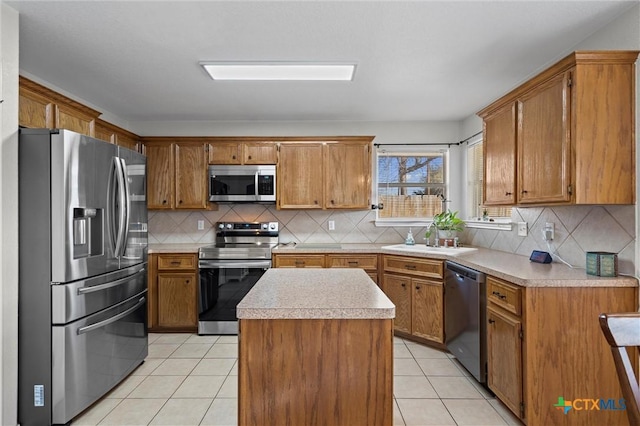 kitchen with light tile patterned floors, brown cabinetry, a sink, stainless steel appliances, and light countertops