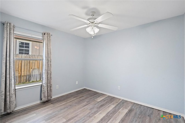 spare room featuring baseboards, wood finished floors, and a ceiling fan