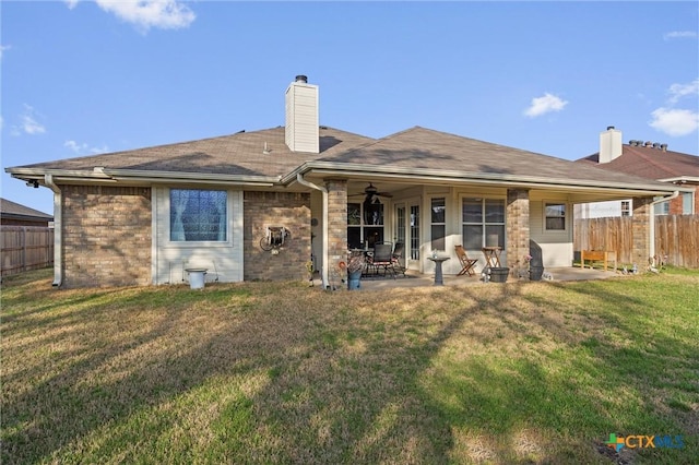 back of house with a lawn, a patio, fence, ceiling fan, and a chimney