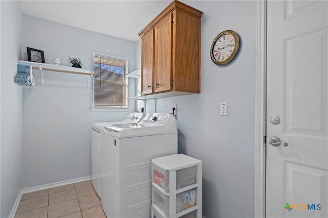 washroom with light tile patterned floors, baseboards, cabinet space, and washing machine and clothes dryer