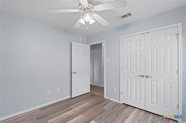 unfurnished bedroom featuring visible vents, ceiling fan, baseboards, wood finished floors, and a closet