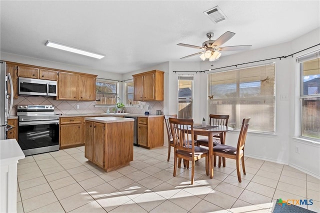 kitchen with tasteful backsplash, visible vents, a kitchen island, light countertops, and stainless steel appliances