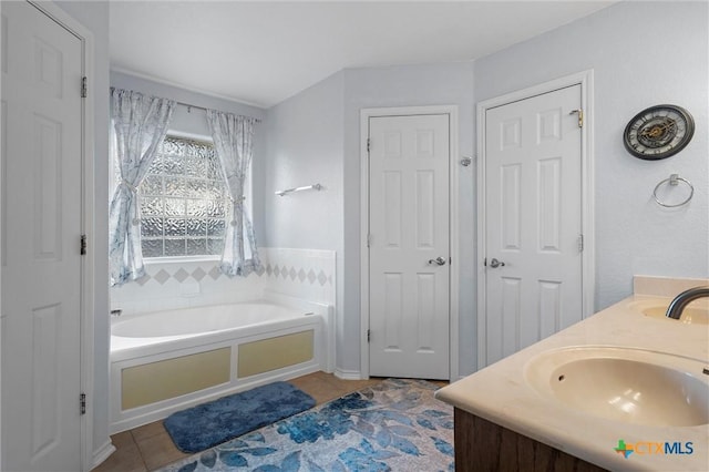 full bath with tile patterned floors, a garden tub, double vanity, and a sink