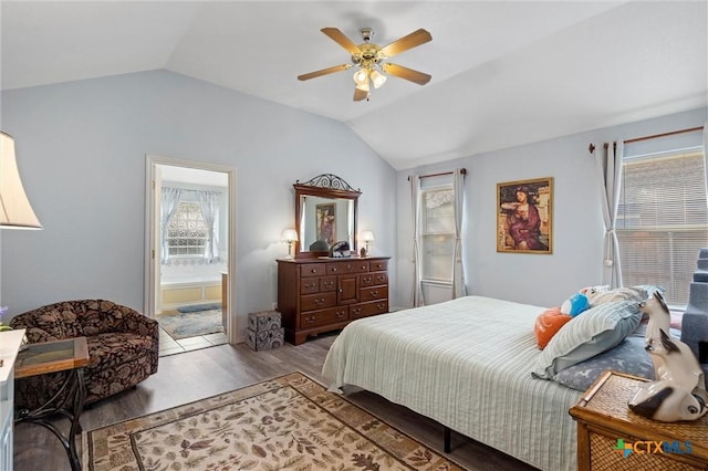 bedroom with a ceiling fan, vaulted ceiling, wood finished floors, and ensuite bath