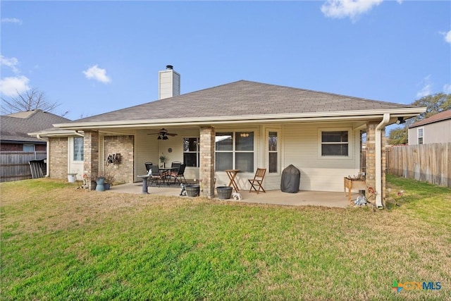 rear view of property featuring fence, a chimney, ceiling fan, a patio area, and a lawn