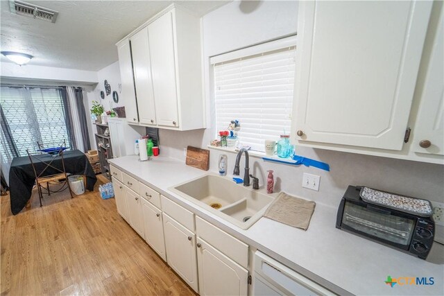 308 Fernwood Cir, Victoria, TX 77901 - kitchen featuring a sink, white cabinets, light wood finished floors, light countertops, and a textured ceiling