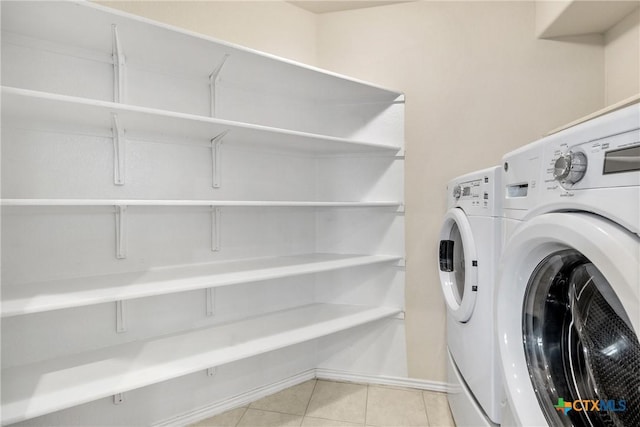 laundry area with baseboards, light tile patterned flooring, laundry area, and washing machine and clothes dryer