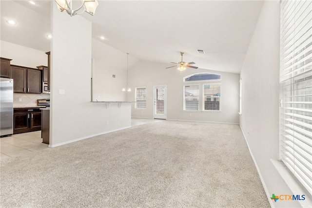 unfurnished living room featuring baseboards, visible vents, high vaulted ceiling, light carpet, and ceiling fan with notable chandelier