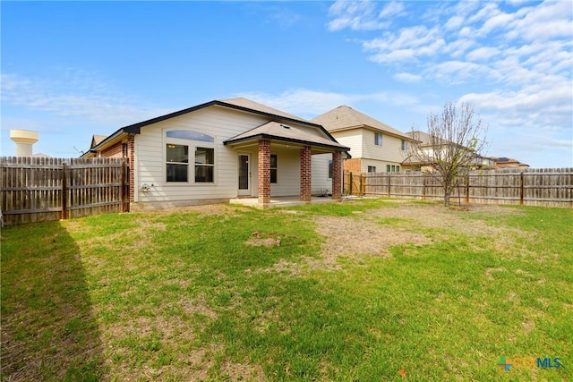 back of house featuring a lawn, a fenced backyard, brick siding, and a patio area