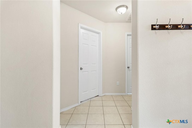 hall with light tile patterned floors, visible vents, and baseboards