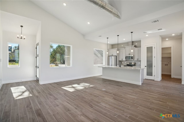 3006 Dew Drop, Horseshoe Bay, TX 78657 - unfurnished living room with plenty of natural light, a chandelier, wood finished floors, baseboards, and recessed lighting