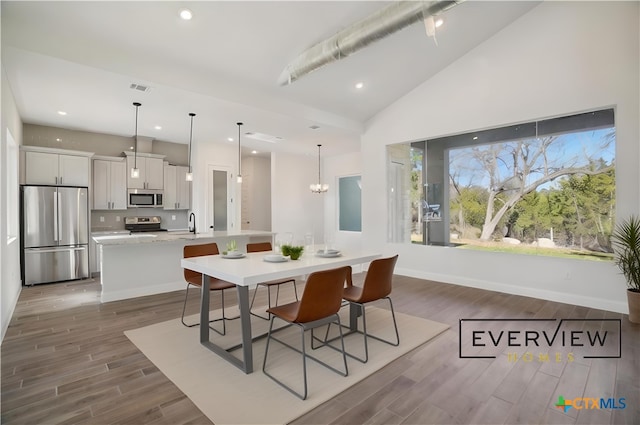 3006 Dew Drop, Horseshoe Bay, TX 78657 - dining room featuring wood finished floors, recessed lighting, a chandelier, baseboards, and high vaulted ceiling