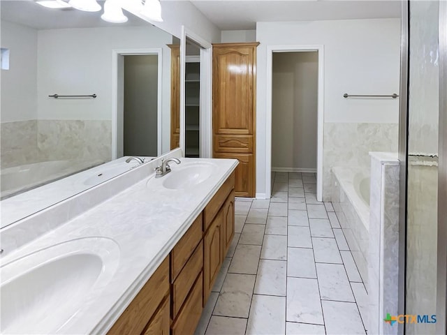 bathroom with tile patterned flooring, vanity, and tiled tub