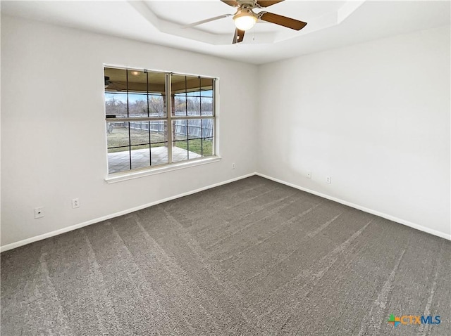 carpeted spare room featuring a raised ceiling and ceiling fan