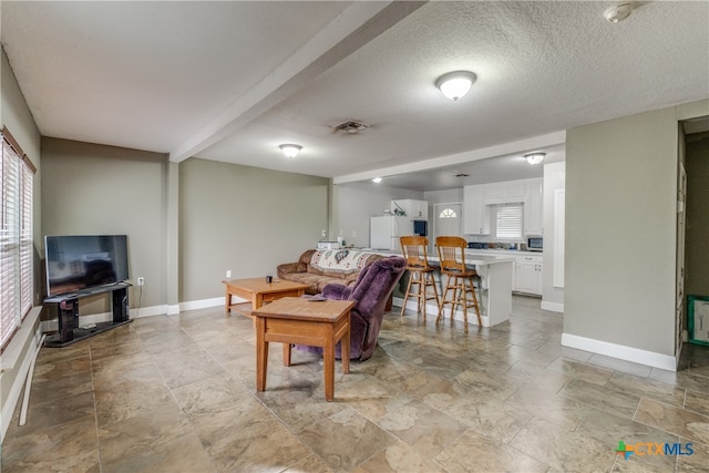 living room with a healthy amount of sunlight, a textured ceiling, and beam ceiling