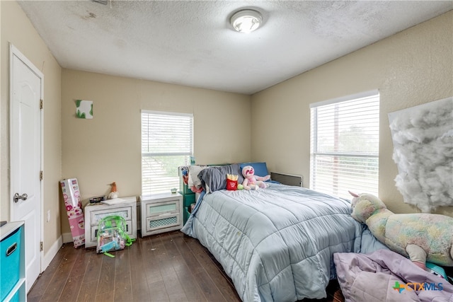 bedroom featuring a textured ceiling and dark hardwood / wood-style floors