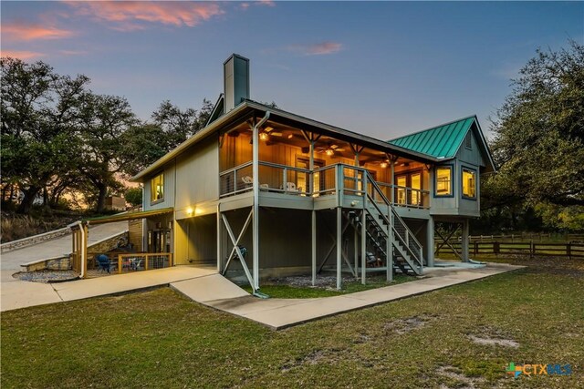 back house at dusk featuring a deck and a lawn