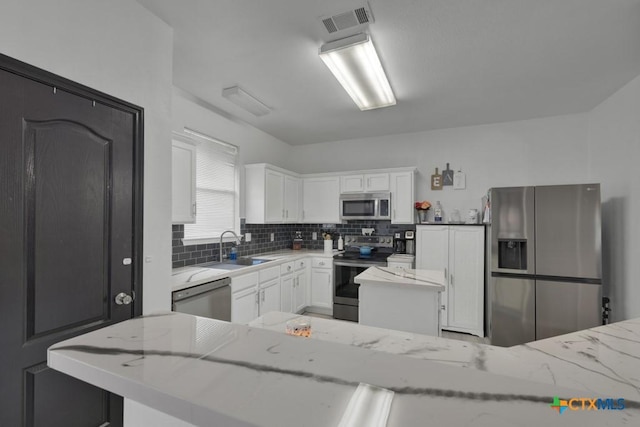 kitchen with light stone countertops, white cabinetry, and appliances with stainless steel finishes