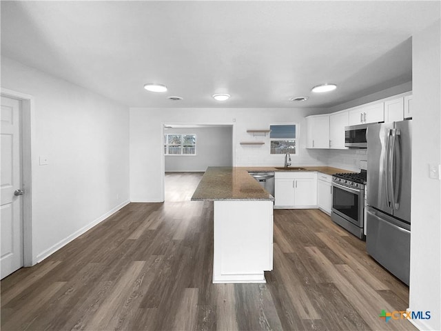 kitchen featuring dark stone countertops, stainless steel appliances, white cabinets, backsplash, and sink