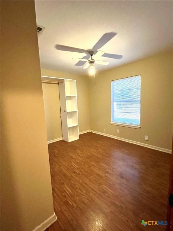 unfurnished bedroom with a closet, dark hardwood / wood-style floors, and ceiling fan