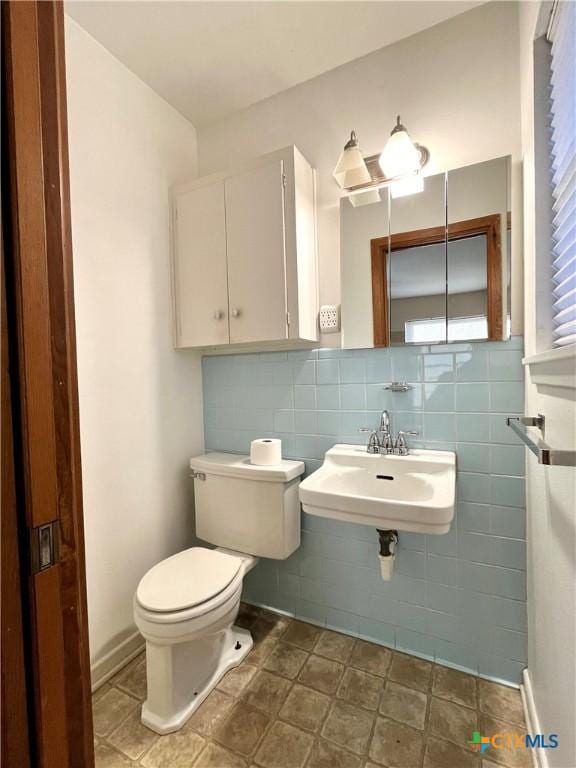 bathroom featuring sink, tile walls, and toilet