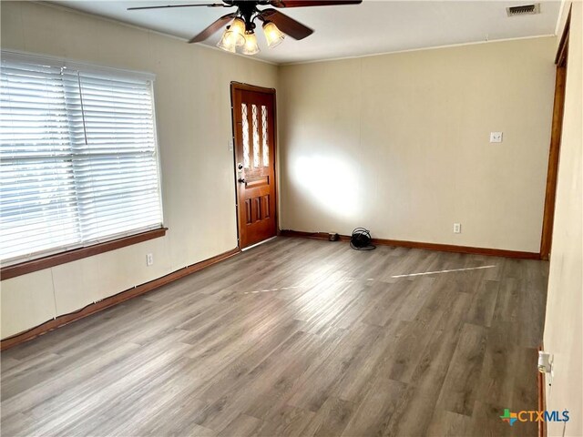 spare room with wood-type flooring, ceiling fan, and crown molding