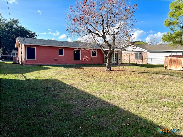 rear view of house featuring a lawn and cooling unit