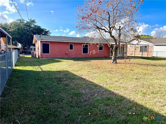 rear view of property featuring a yard and central AC unit