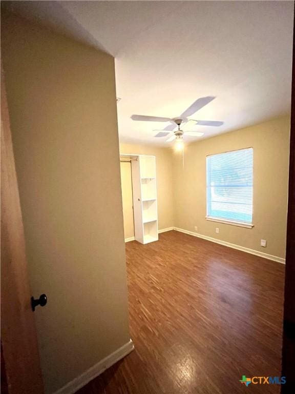 empty room with ceiling fan and dark hardwood / wood-style flooring