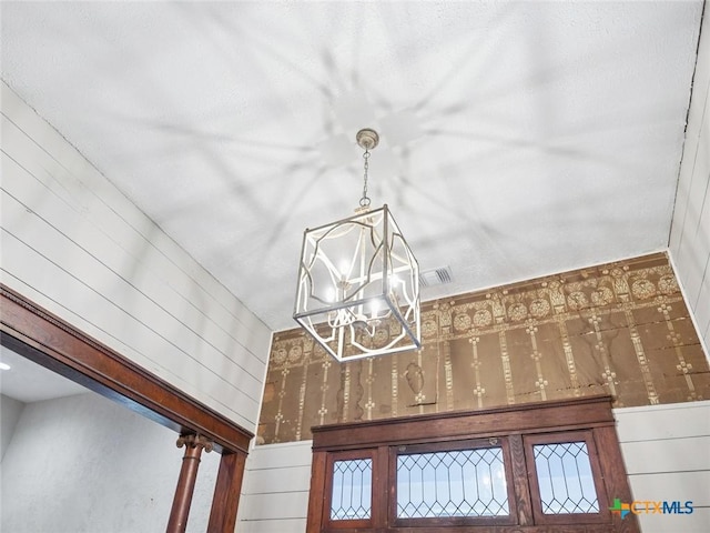 details featuring an inviting chandelier and wood walls