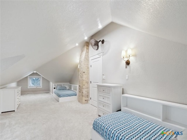 bedroom featuring light colored carpet, lofted ceiling, and a textured ceiling