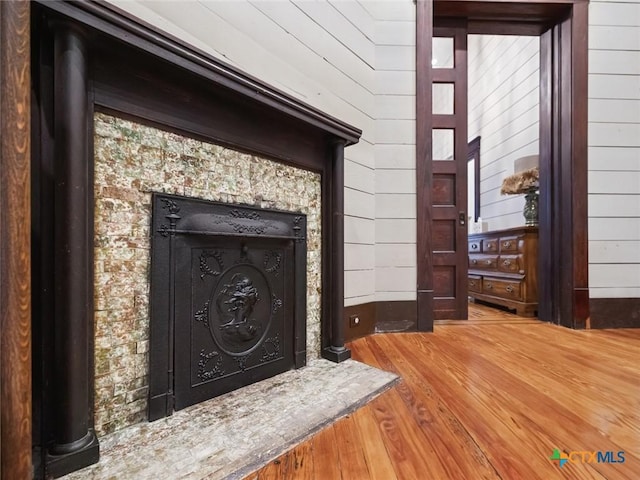 interior details with hardwood / wood-style floors, a fireplace, and wooden walls