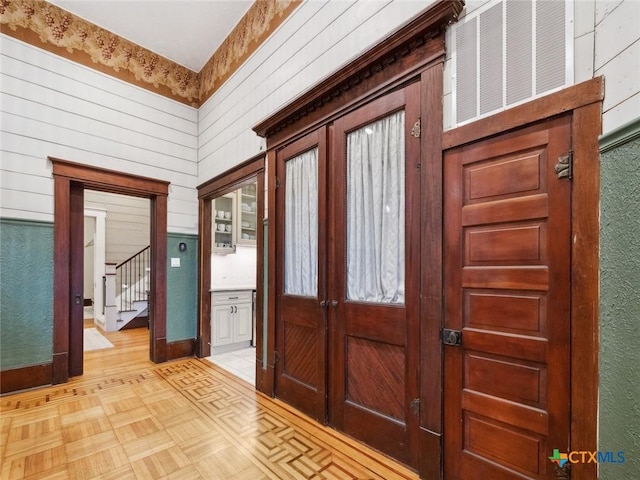 entrance foyer featuring light parquet floors and wooden walls