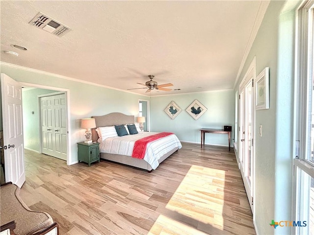 bedroom with light wood-type flooring, ceiling fan, visible vents, and ornamental molding