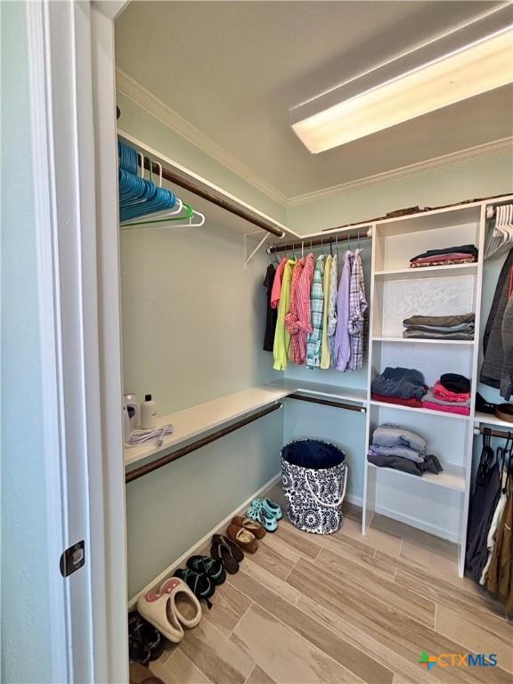 walk in closet with wood finish floors